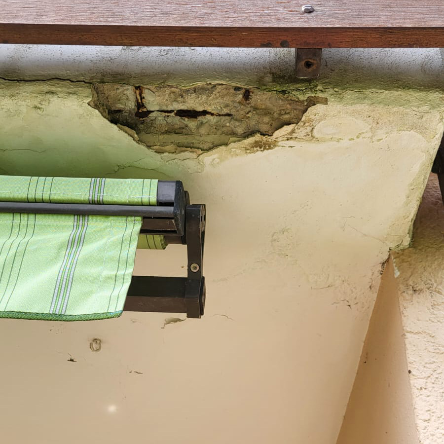 Betonabplatzungen und Korrosionsschäden an der Balkonplatte durch eindringende Feuchtigkeit. Sichtbare Bewehrung und fortschreitende Substanzschäden.